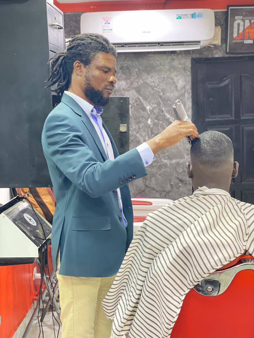 Stylist in a sleek teal blazer trimming a client's hair